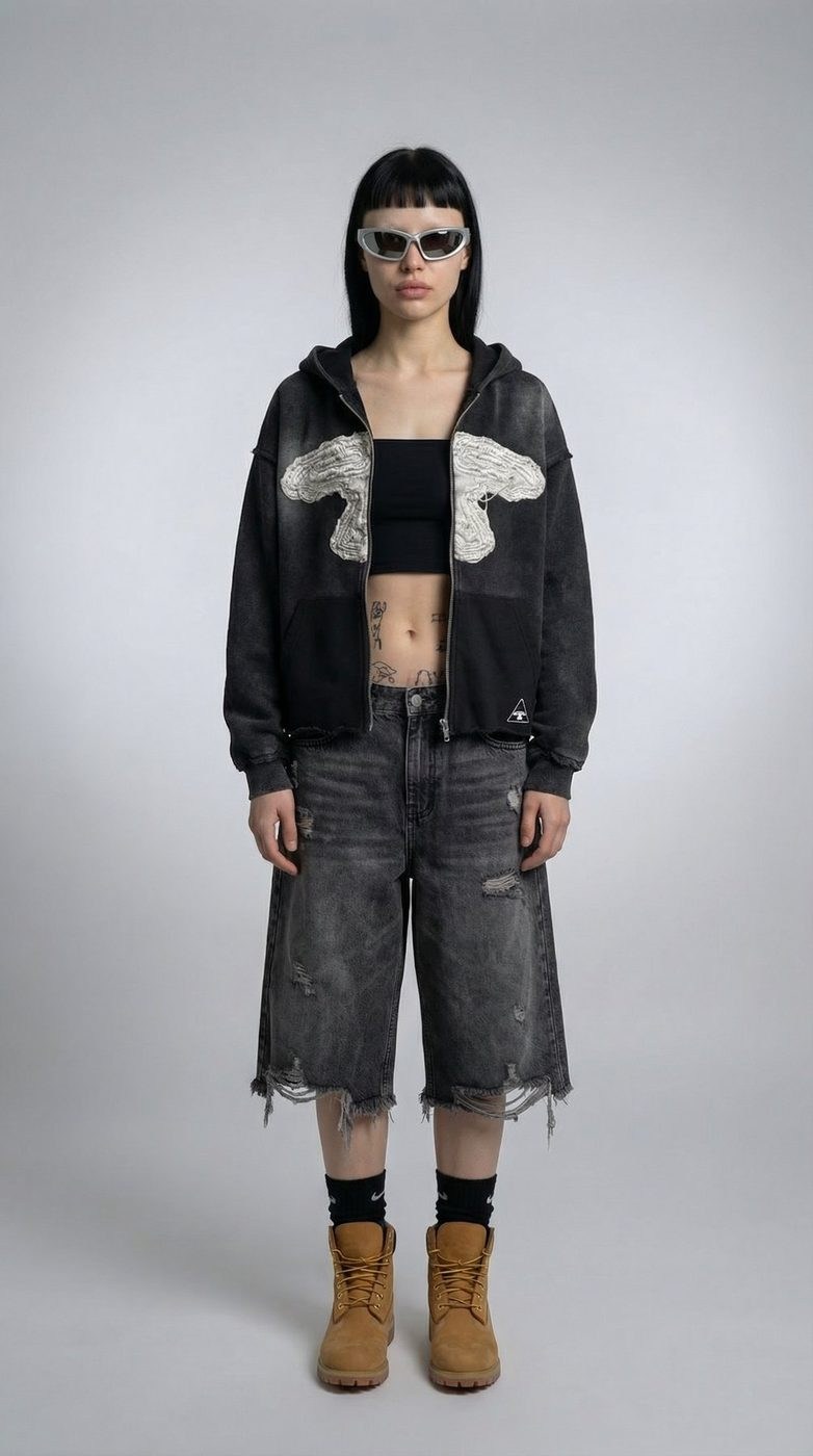 Modelo feminina com o zip-up 5LOOP, calções de ganga e botas, em estúdio